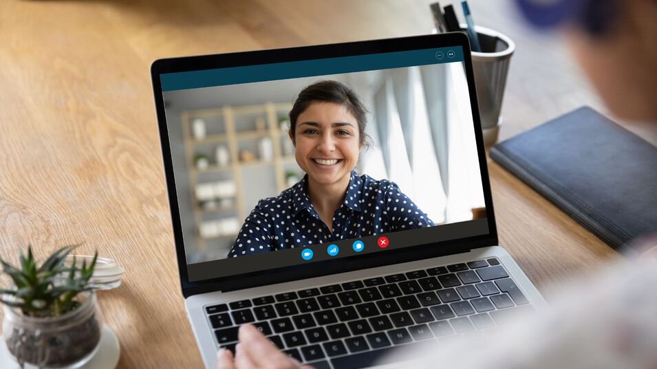 A laptop screen displaying a virtual meeting with a woman discussing the benefits from outsourcing